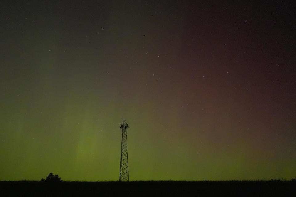 A communications tower is silhouetted against the northern lights on Saturday, May 11, 2024, near St. / Credit: Charlie Riedel / AP