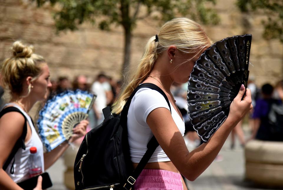 Two women use fans to fight the scorching heat during a heatwave in Seville on June 13, 2022. The city recently got the world's first named heat wave.