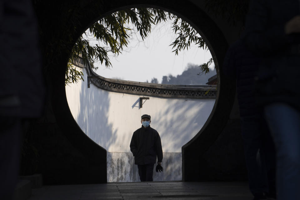 A visitors wearing a mask walks towards a circular doorway at a park in Beijing on Thursday, March 5, 2020. In places around the globe, a split was developing. China has been issuing daily reports of new infections that are drastically down from their highs, factories there are gradually reopening and there is a growing sense that normalcy might not be that far off. Meanwhile, countries elsewhere are seeing escalating caseloads and a litany of cancellations, closures, travel bans and supply shortages. (AP Photo/Ng Han Guan)