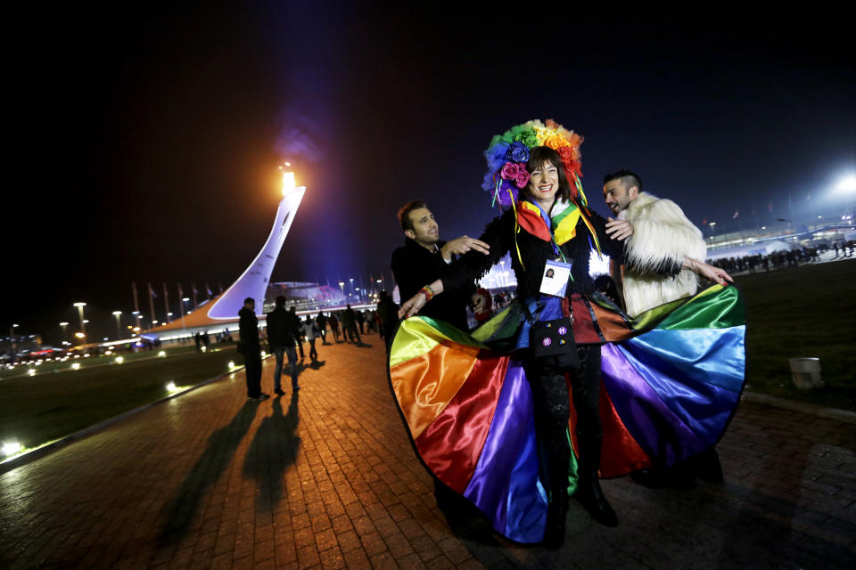 Vladimir Luxuria, center, a former Communist lawmaker in the Italian parliament and prominent crusader for transgender rights, is led away by friends to attend a women's ice hockey match after posing for photos on the Olympic Plaza at the 2014 Winter Olympics, Monday, Feb. 17, 2014, in Sochi, Russia. Luxuria was soon after detained by police upon entering the Shayba Arena. (AP Photo/David Goldman)