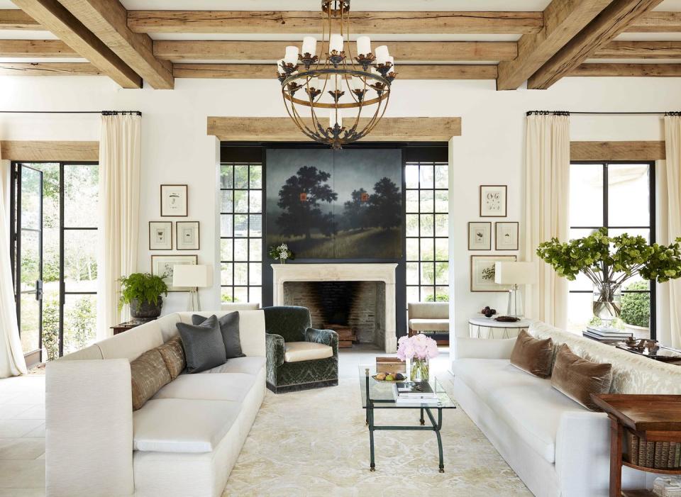 two sofas face each other in a large living space with a landscape painting hanging above the fireplace