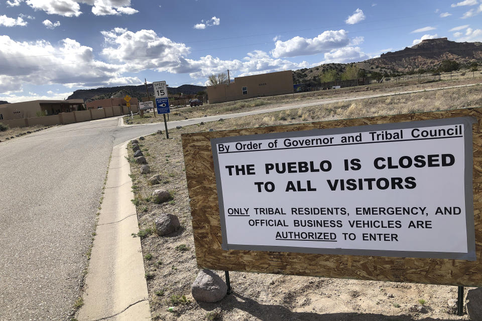 A sign at the Native American community of San Idefonso Pueblo, N.M., urges visitors to stay away as small Indian pueblos throughout the state seek to shield themselves from COVID-19 infection, Thursday, April 23, 2020. San Ildefonso was invited to participate in universal testing by state health officials. (AP Photo/Morgan Lee)