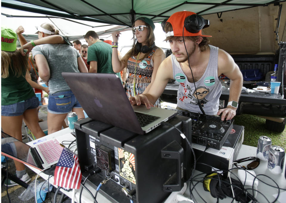 In this Saturday, Nov. 9, 2013 photo, DJs ZAZ, left, and Joseph Michael provide music for tailgaters at a row of tents set up by Generation Opportunity, a national conservative organization that targets young adults, in the parking lot of Sun Life Stadium before the start of an NCAA college football game between Miami and Virginia Tech, in Miami Gardens, Fla. It may be the hottest tailgate party at the University of Miami's homecoming game, but the 100-yard stretch of free pizza and party tents, is also a carefully crafted strategy aimed at getting students to opt out of President Barack Obama's controversial new health law. (AP Photo/Wilfredo Lee)