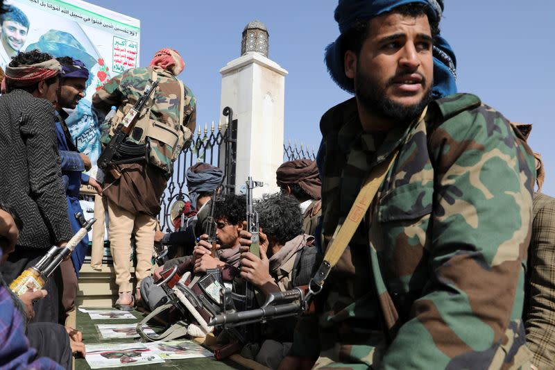 Armed Houthi followers sit next to a coffin of a Houthi fighter killed in recent fighting against government forces in Yemen's oil-rich province of Marib, following a funeral procession in Sanaa