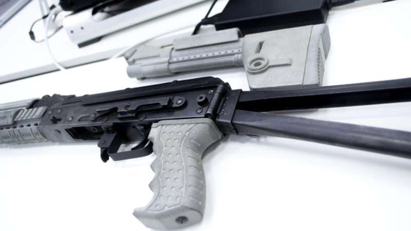 Parts of a 3D-printed semi-automatic rifle against a white background.