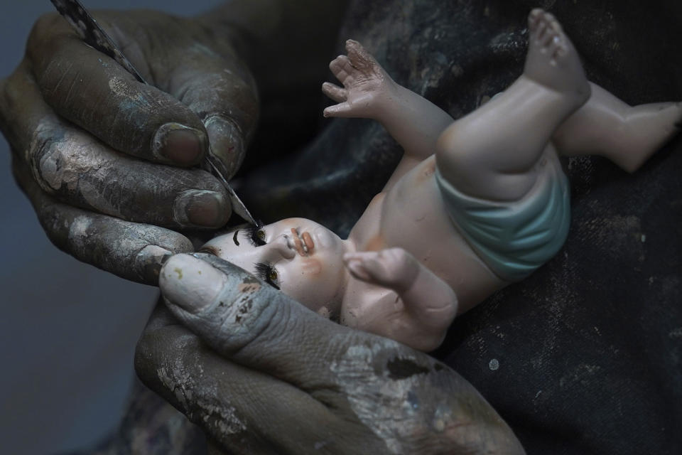 Un hombre repara una estatua del niño Dios en preparación para la fiesta del "Día de la Candelaria" en la Ciudad de México, el miércoles 25 de enero de 2023. (AP Foto/Marco Ugarte)