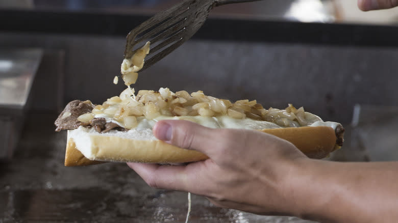 Person making Geno's Philly cheesesteak