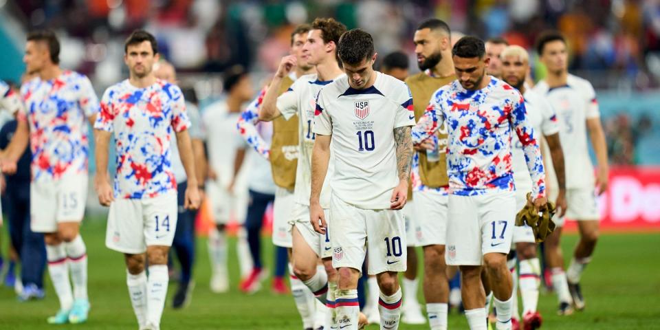 USMNT players walk off the field at the World Cup, with several of the looking down.