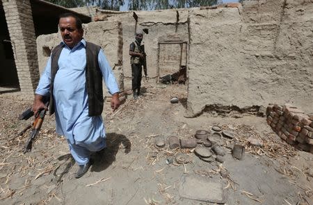 A policeman in plain clothes (L) walks out of a damaged house, which witnesses said belonged to Hafeez Brohi, wanted in connection with bombings in Shikarpur and suspected in many other blasts in Sindh province, on the outskirts of Shikarpur, Pakistan March 19, 2017. Picture taken March 19, 2017. REUTERS/Akhtar Soomro