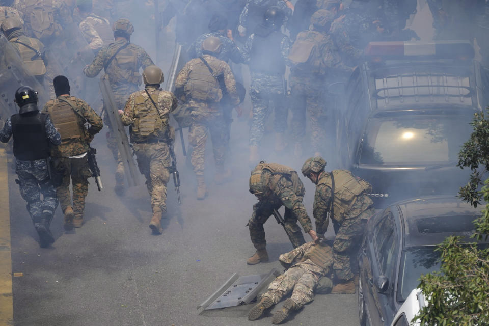 Lebanese special forces soldiers, right, remove their comrade who faints from the tear gas during a protest for retired army soldiers and other protesters who are demanding better pay, in Beirut, Lebanon, Wednesday, March 22, 2023. Lebanese security forces are firing tear gas to disperse hundreds of protesters who tried to break through a fence leading to the government headquarters in downtown Beirut. The protest comes amid widespread anger over the harsh economic conditions in the country. (AP Photo/Hussein Malla)