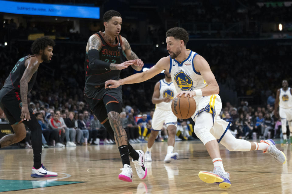 Golden State Warriors guard Klay Thompson (11) drives while Washington Wizards forward Kyle Kuzma, center, defends during the first half of an NBA basketball game in Washington, Tuesday, Feb. 27, 2024. (AP Photo/Manuel Balce Ceneta)