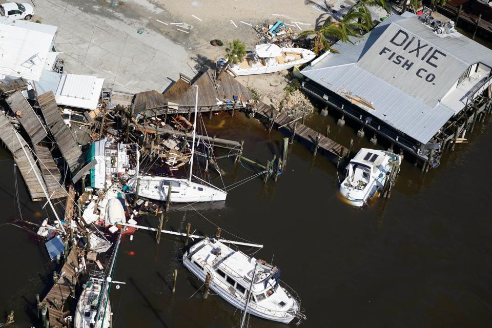 Damages boats lie on the land and water in the aftermath of Hurricane Ian, Thursday, Sept. 29, 2022, in Fort Myers, Fla. (AP Photo/Wilfredo Lee)