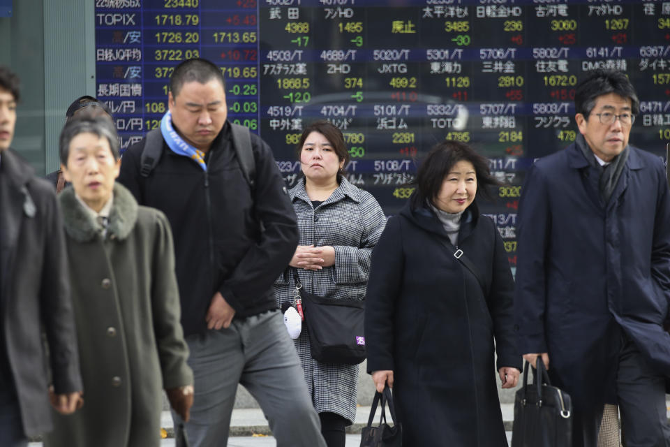 People walk by an electronic stock board of a securities firm in Tokyo, Monday, Dec. 9, 2019. Japan's economy grew at an annual rate of 1.8% in July-September, according to revised government data, better than the modest annual pace of 0.2% it gave as an earlier estimate. (AP Photo/Koji Sasahara)