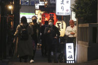 People wearing face masks to protect against the spread of the coronavirus walk on a street lined with bars and restaurants in Tokyo Wednesday, March 16, 2022. Japan’s Prime Minister Fumio Kishida on Wednesday announced plans to fully lift coronavirus restrictions on March 21 as new infections driven by the highly contagious omicron variant slow. (AP Photo/Koji Sasahara)