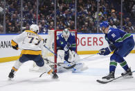 Vancouver Canucks goalie Thatcher Demko, center, stops Nashville Predators' Luke Evangelista, left, as Vancouver's Nikita Zadorov watches during the second period in Game 1 of an NHL hockey Stanley Cup first-round playoff series in Vancouver, British Columbia, on Sunday, April 21, 2024. (Darryl Dyck/The Canadian Press via AP)