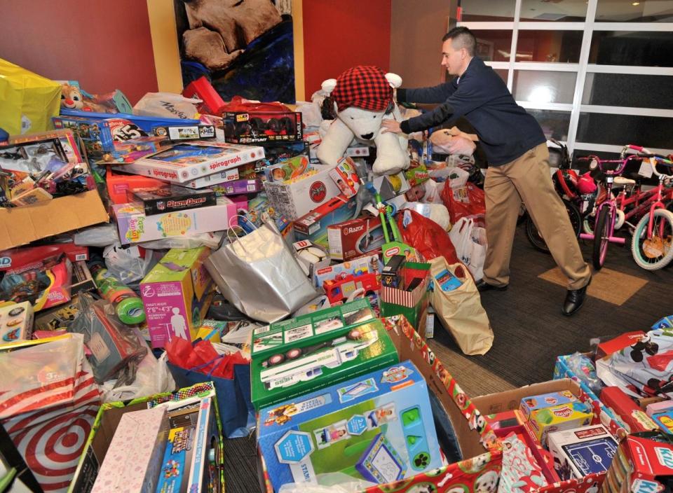 John McKinley places a stuffed bear on a pile of donated toys during the 9th annual Braintree Christmas Party in 2018.  The toys are distributed through the Marge Crispin Center.