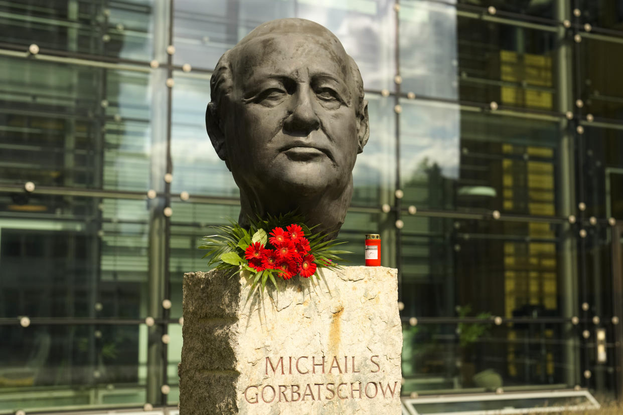 Flowers and a candle are placed on a plinth displaying a bust of former Soviet President Mikhail Gorbachev.