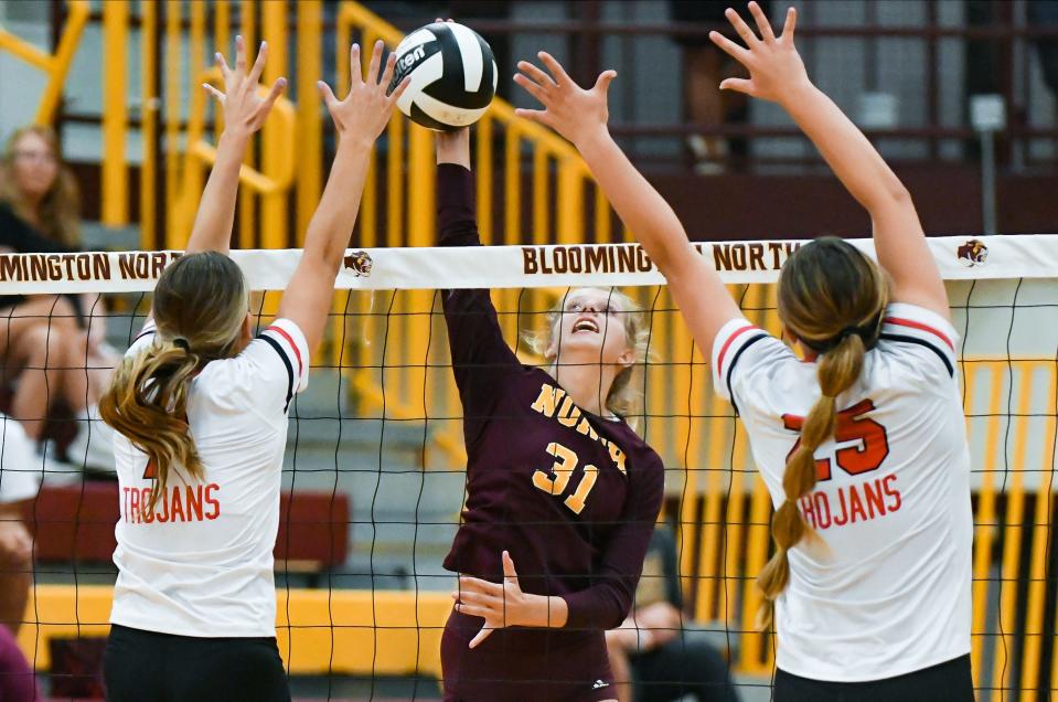 Bloomington North’s Kenli Sullivan (31) hits the ball past Center Grove’s Ellen Zapp (left) and Ava Mardis (25) during the volleyball match against Center Grove at North on Monday, August 21, 2023.
