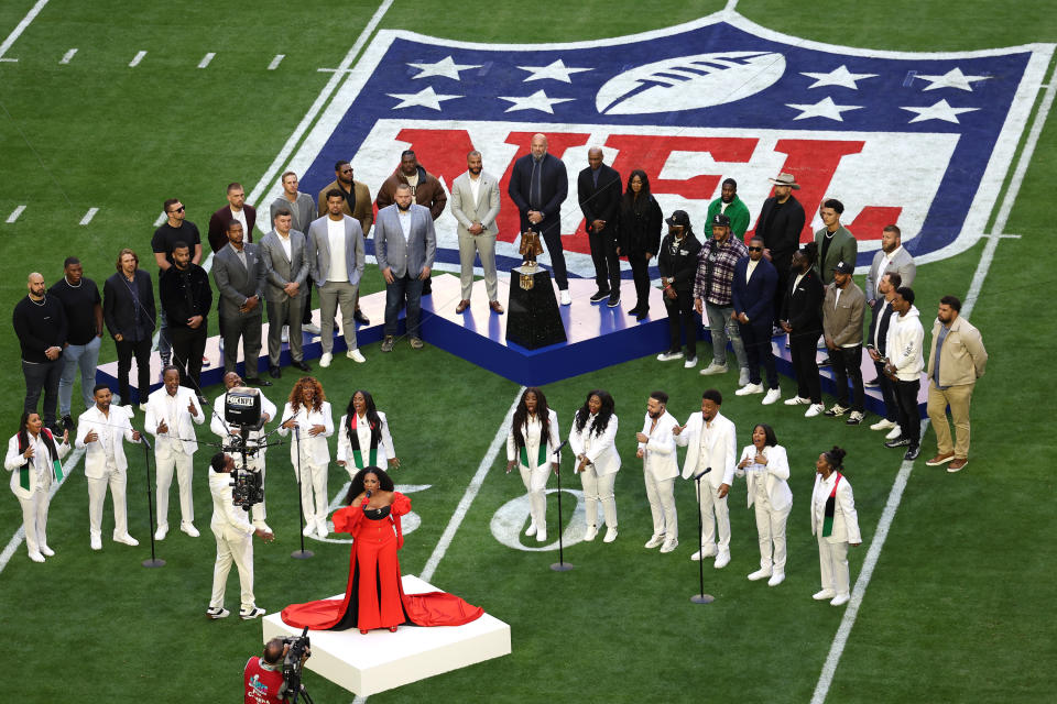 Ralph performing on the field with a choir standing behind her