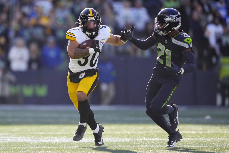 Pittsburgh Steelers running back Jaylen Warren (30) tries to get past Seattle Seahawks cornerback Devon Witherspoon (21) in the first half of an NFL football game Sunday, Dec. 31, 2023, in Seattle. (AP Photo/Lindsey Wasson)
