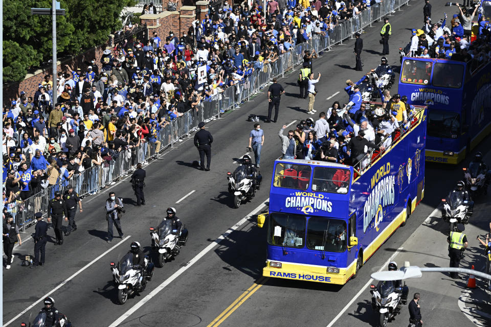 Buses carrying Los Angeles Rams players and coaches drive past fans during the team's victory parade in Los Angeles, Wednesday, Feb. 16, 2022, following their win Sunday over the Cincinnati Bengals in the NFL Super Bowl 56 football game. (AP Photo/Kyusung Gong)