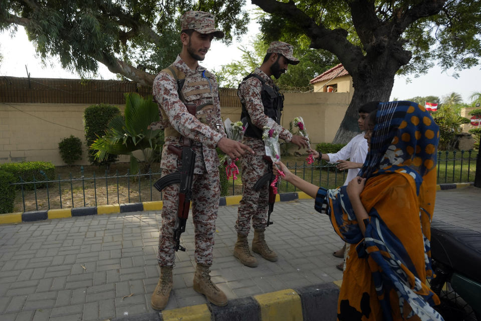 Pakistani woman give a flower to Army during a rally to show solidarity with Pakistan's army in Karachi, Pakistan, Friday, May 19, 2023. . (AP Photo/Fareed Khan)