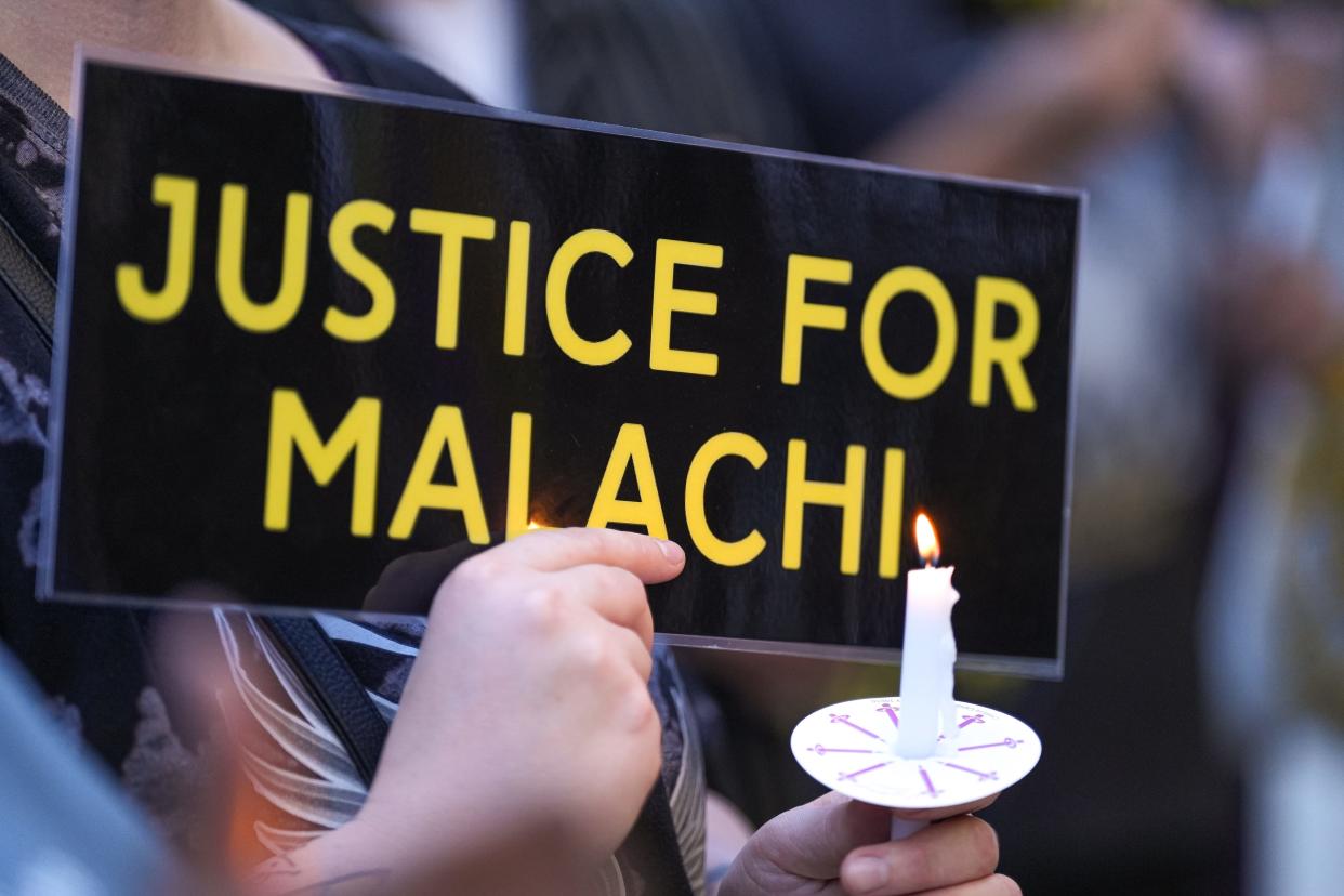 A community member holds a sign and candle at a vigil for Malachi Williams outside the San Marcos Public Library on Thursday in San Marcos. Williams was killed by San Marcos police April 11.