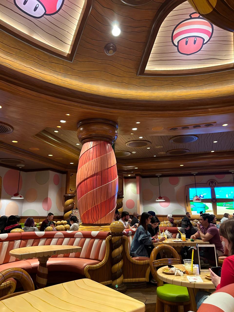 Interior of the cafe with pink and white tables and booths, columns, and mushrooms on the ceilings.