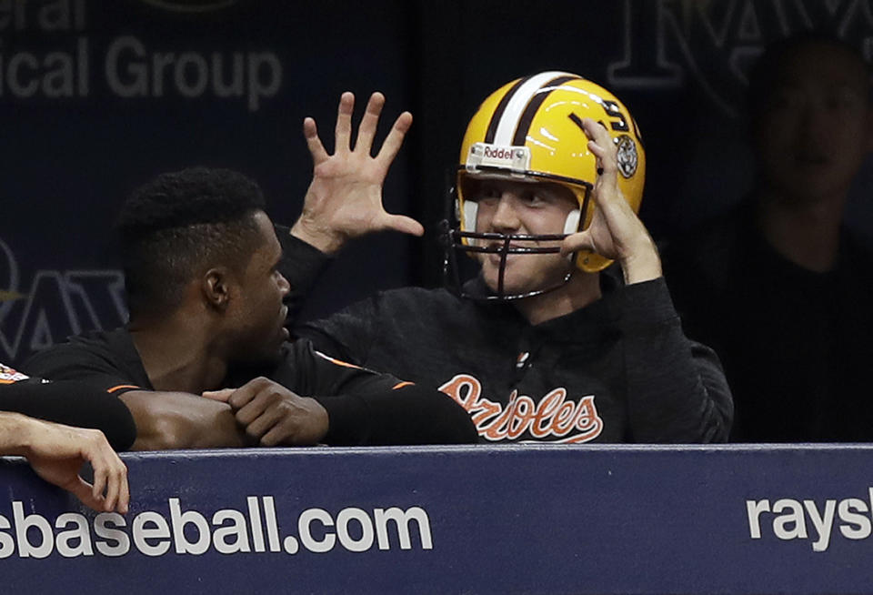 Baltimore Orioles relief pitcher David Hess returns wearing an LSU football helmet after being hit in the eye by a football during pregame. (AP)