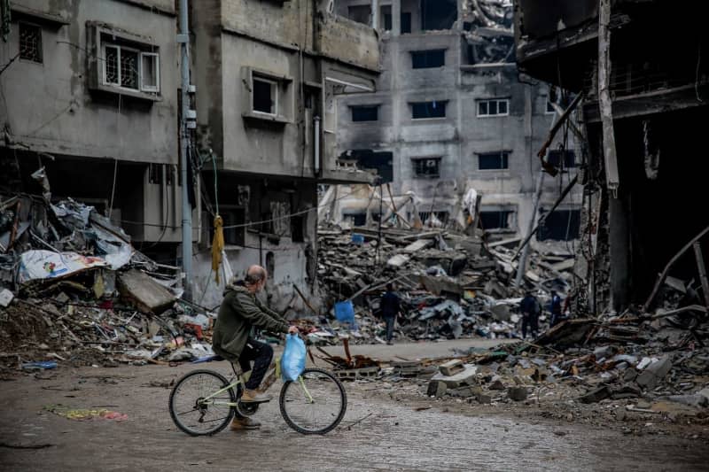 A Palestinian man rides his bike past destroyed buildings in the Sheikh Radwan neighbourhood in Gaza City, after one hundred days of the Isarel-Hamas war. Omar Ishaq/dpa