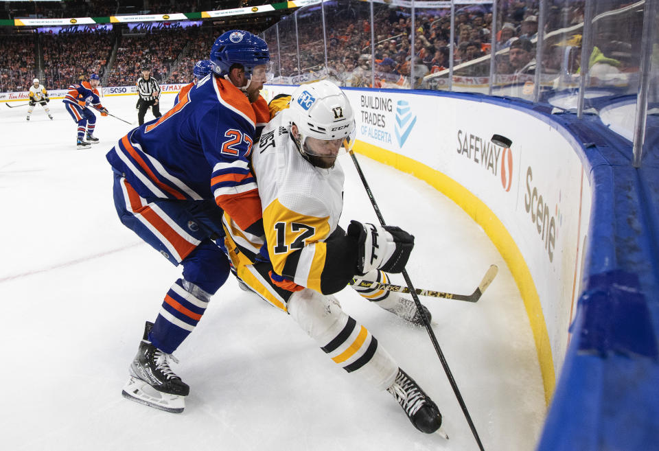 Pittsburgh Penguins' Bryan Rust (17) and Edmonton Oilers' Brett Kulak (27) battle for the puck during third-period NHL hockey game action in Edmonton, Alberta, Monday, Oct. 24, 2022. (Jason Franson/The Canadian Press via AP)