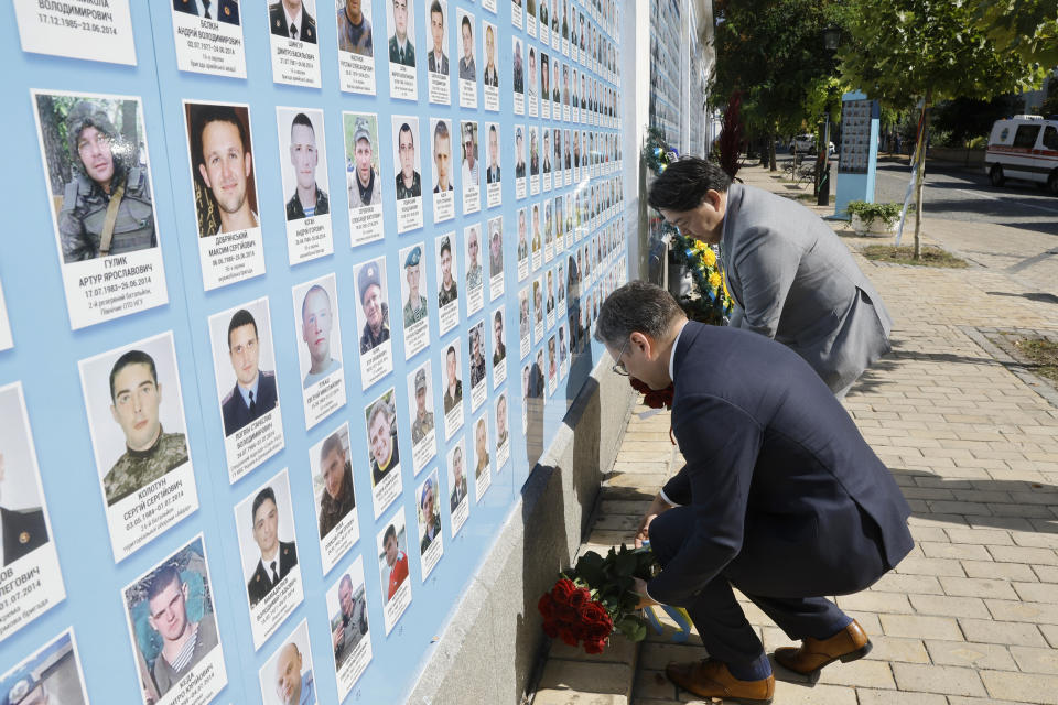 Ukraine's Foreign Minister Dmytro Kuleba, front, and his Japanese counterpart Yoshimasa Hayashi pay a visit to the Memory Wall of Fallen Defenders of Ukraine in Kyiv, Ukraine, Saturday, Sept. 9, 2023. Japanese Foreign Minister Hayashi arrived in Ukraine's capital for an unannounced visit where he will meet with top Ukrainian officials. (Sergey Dolzhenko/pool via AP)