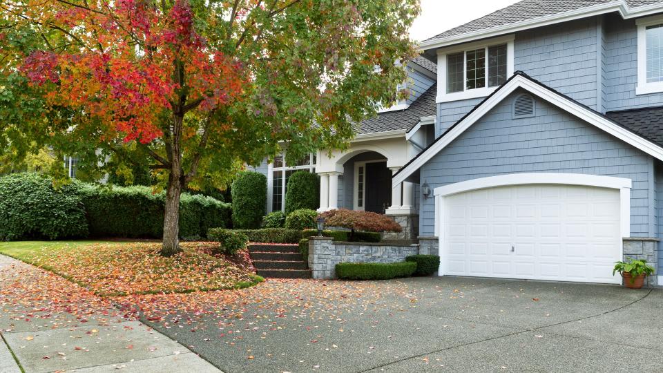 Driveway to front walkway view of partial front of residential home during early autumn season.