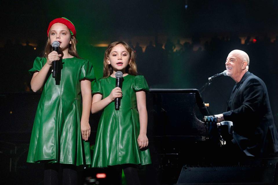 <p>Myrna M. Suarez/Getty Images</p> Billy Joel performs with his daughters Della and Remy at Madison Square Garden