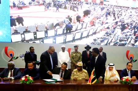 Deputy Head of Sudanese Transitional Military Council, Mohamed Hamdan Dagalo, and Sudan's opposition alliance coalition's leader Ahmad al-Rabiah, sign power sharing deal, as guests and partners witness, in Khartoum