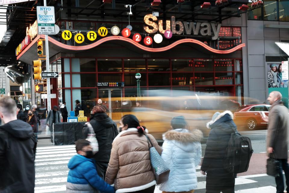 People stand outside a subway station in Times Square, New York City