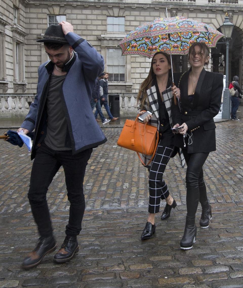 People arrive smiling despite the rain for the first day of London Fashion Week, in London, Friday, Feb. 14, 2014. (AP Photo/Alastair Grant)