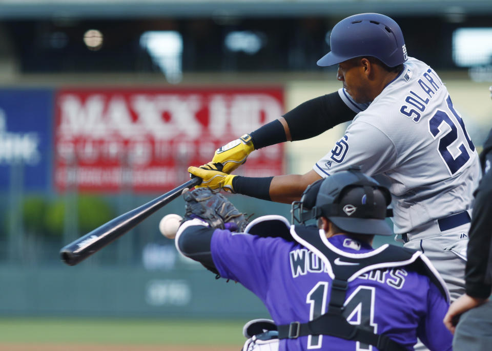 San Diego Padres' Yangervis Solarte, back, swings as Colorado Rockies catcher Tony Wolters fields a pitch in the first inning of a baseball game, Monday, April 10, 2017, in Denver. (AP Photo/David Zalubowski)