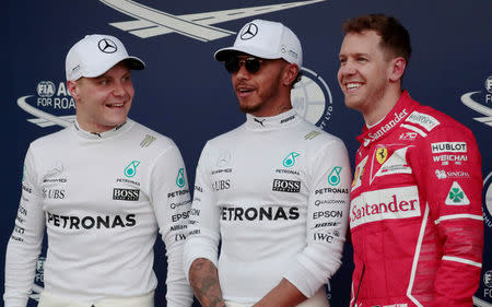 Formula One - F1 - Australian Grand Prix - Melbourne, Australia - 25/03/2017 Mercedes driver Lewis Hamilton (C) of Britain reacts after setting pole position in qualifying alongside team mate Valtteri Bottas (L) of Finland and Ferrari's Sebastian Vettel of Germany. REUTERS/Jason Reed