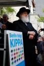 A member of the Jewish Community stands on the stage during a demonstration in front of a Jewish synagogue, to denounce an anti-Semitic attack on a young man wearing a kippa in the capital earlier this month, in Berlin, Germany, April 25, 2018. The sign reads: "Berlin wears kippa." REUTERS/Fabrizio Bensch