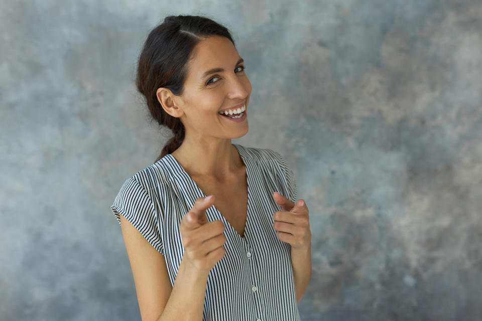 A woman makes finger gun motion and laughs