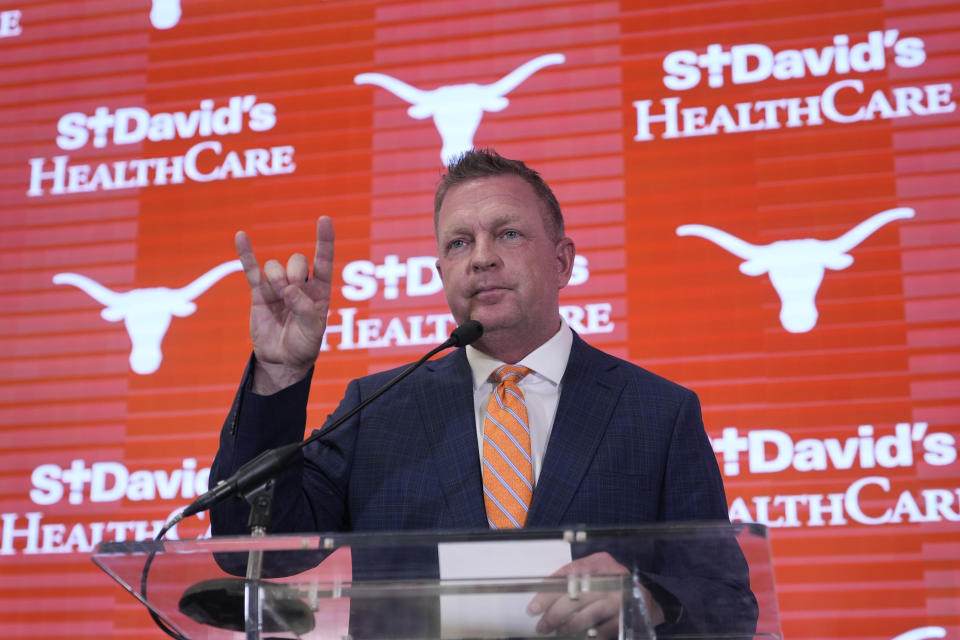 Jim Schlossnagle flashes a hook'em sign as he speaks at a news conference after he was introduced as the new NCAA college head baseball coach at Texas, Wednesday, June 26, 2024, in Austin, Texas. Schlossnagle left rival program Texas A&M. (AP Photo/Eric Gay)