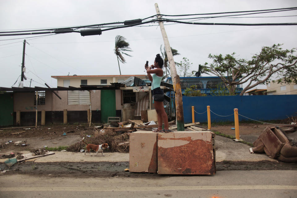 <p>A woman stands on an overturned refrigerator while trying to get a mobile phone signal, after Hurricane Maria hit the island in September, in Toa Baja, Puerto Rico, Oct. 18, 2017. (Photo: Alvin Baez/Reuters) </p>