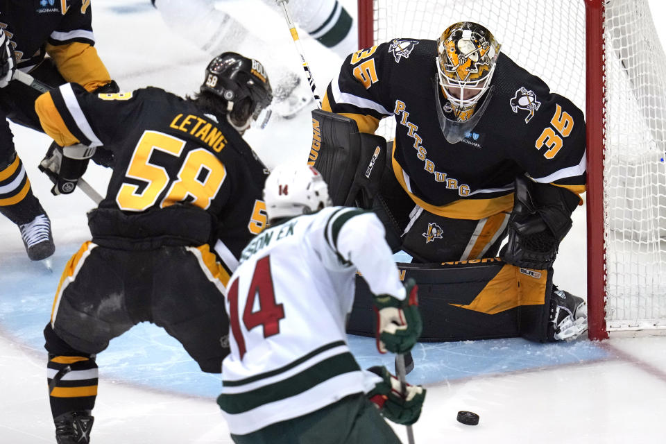 Pittsburgh Penguins goaltender Tristan Jarry (35) blocks a shot by Minnesota Wild's Joel Eriksson Ek (14) with Kris Letang (58) helping defend during the first period of an NHL hockey game in Pittsburgh, Thursday, April 6, 2023. (AP Photo/Gene J. Puskar)