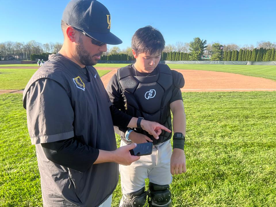 Upper Arlington catcher Mark Lee and pitching coach Joseph Juza discuss strategy while using the GoRout communication system.