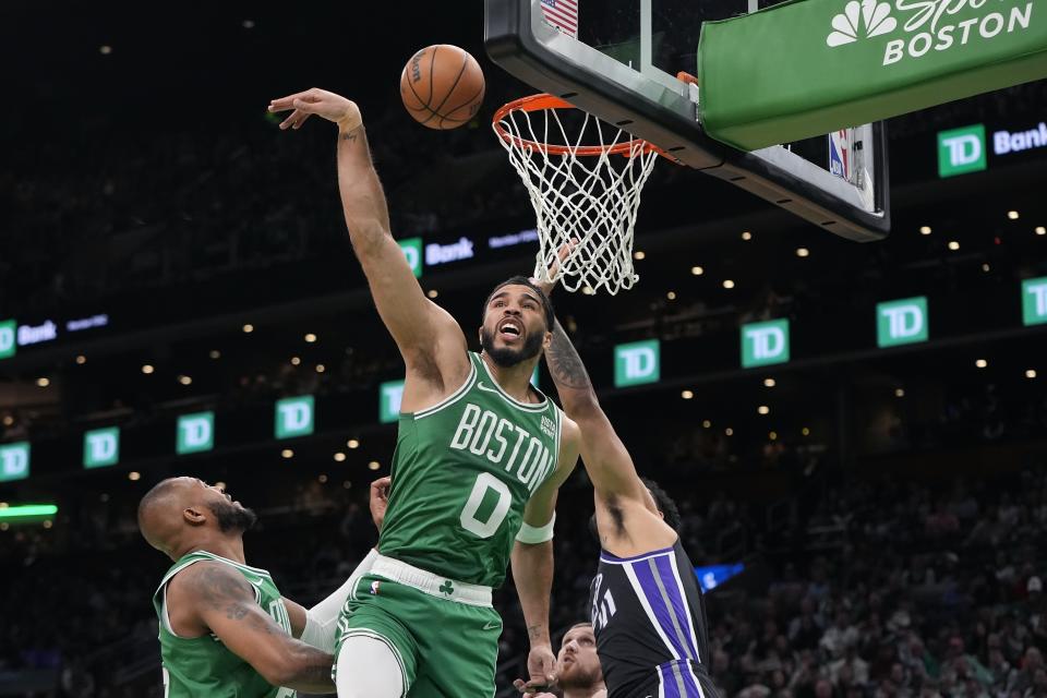 Boston Celtics' Jayson Tatum (0) and Sacramento Kings' Trey Lyles, right, reach for a rebound during the first half of an NBA basketball game Friday, April 5, 2024, in Boston. (AP Photo/Michael Dwyer)