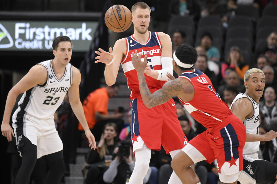 Washington Wizards' Kristaps Porzingis, center, passes the ball to teammate Bradley Beal, second from right, as they are defended by San Antonio Spurs' Zach Collins (23) and Jeremy Sochan, right, during the first half of an NBA basketball game, Monday, Jan. 30, 2023, in San Antonio. (AP Photo/Darren Abate)