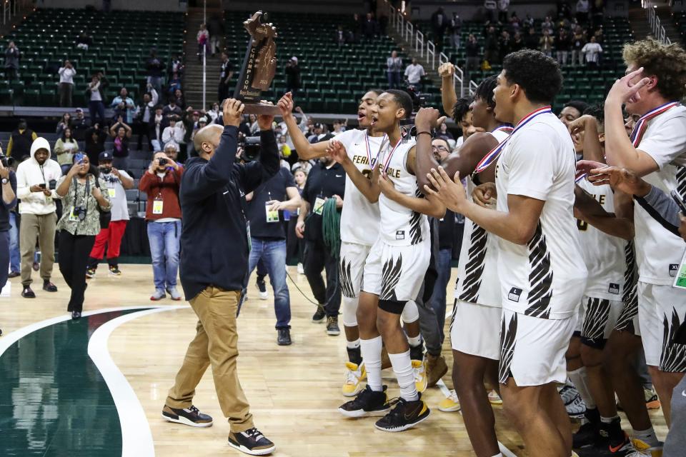 Ferndale head coach Juan Rickman lifts the trophy as players and coaches celebrate their 44-38 win over Grand Rapids South Christian in the MHSAA boys Division 2 final at Breslin Center in East Lansing on Saturday, March 25, 2023.