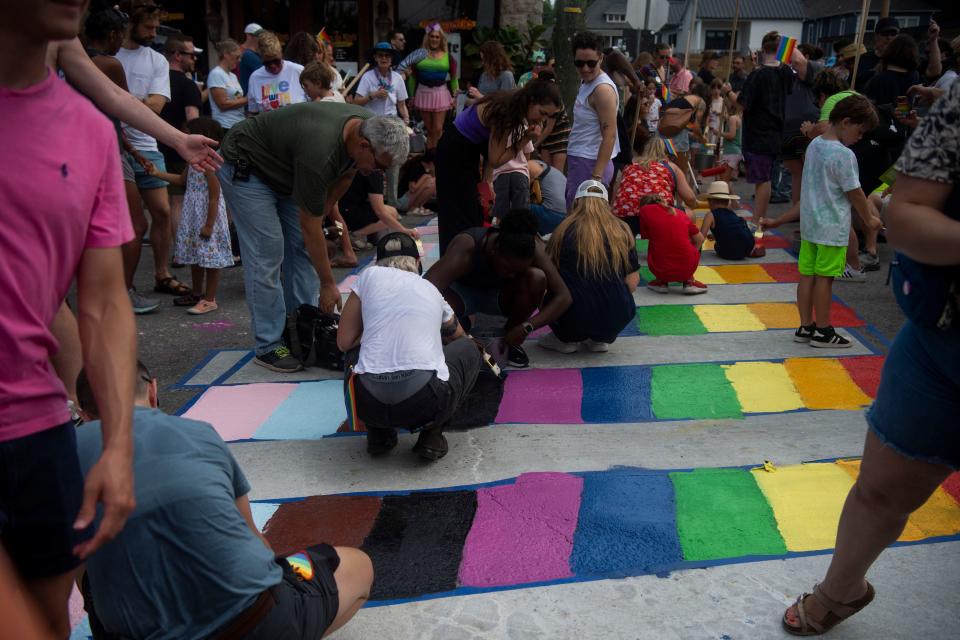 Community members gather to paint a rainbow crosswalk at the intersection surrounding the Lipstick Lounge in Nashville, Tenn., Saturday, June 29, 2024.