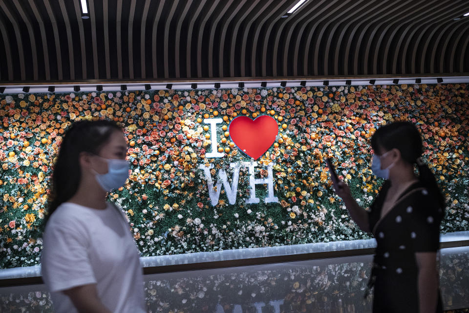 WUHAN, CHINA - AUGUST 11: (CHINA OUT) Citizens wear masks while walking by a design of “I Heart Wuhan” on the wall at a shopping mall on August 11, 2021 in Wuhan, Hubei Province, China. Local media has reported new cases of Covid-19 as Wuhan launches a city-wide nucleic acid testing program. It is the first time new cases of community transmission have been recorded in Wuhan since May 2020. The new wave of Covid-19 started in Nanjing, prompting provinces and cities to take action to fend off the coronavirus. (Photo by Getty Images)